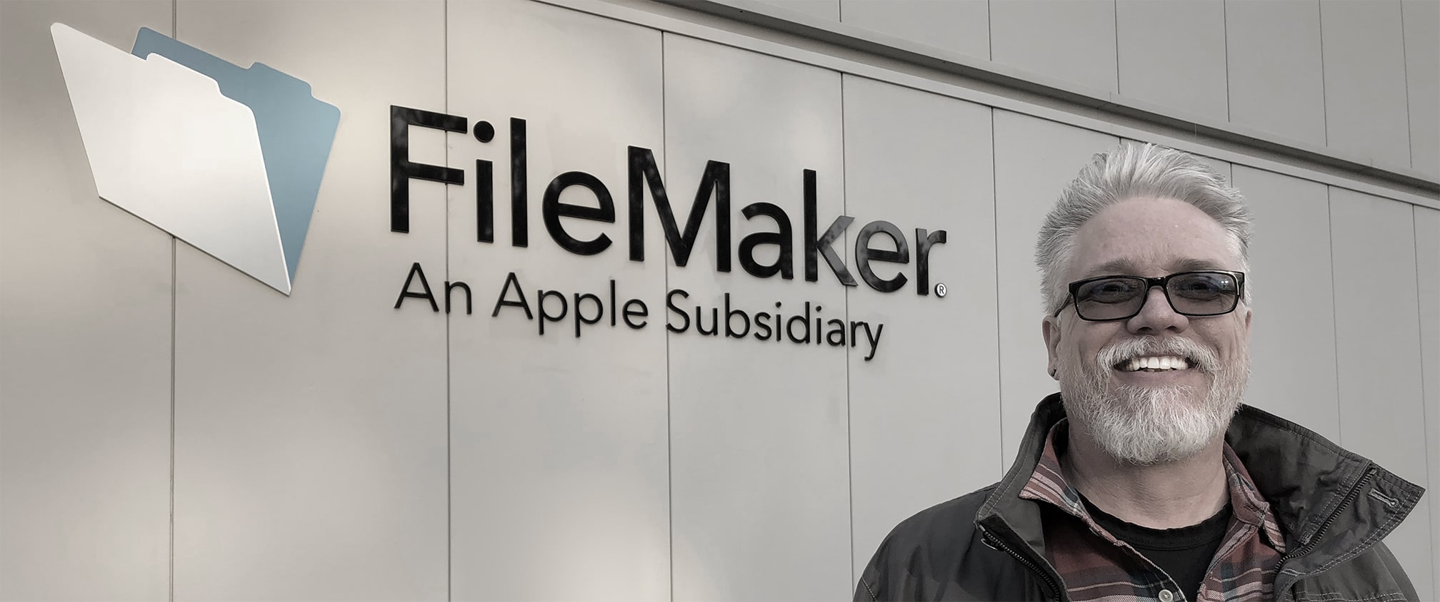 ai_robot_li Smiling person standing outside the FileMaker headquarters, with the company logo and tagline “An Apple Subsidiary” visible on the building wall.