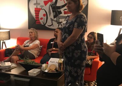 People gathered in an office lounge for a casual discussion or event, seated around a coffee table with modern decor and artwork in the background.