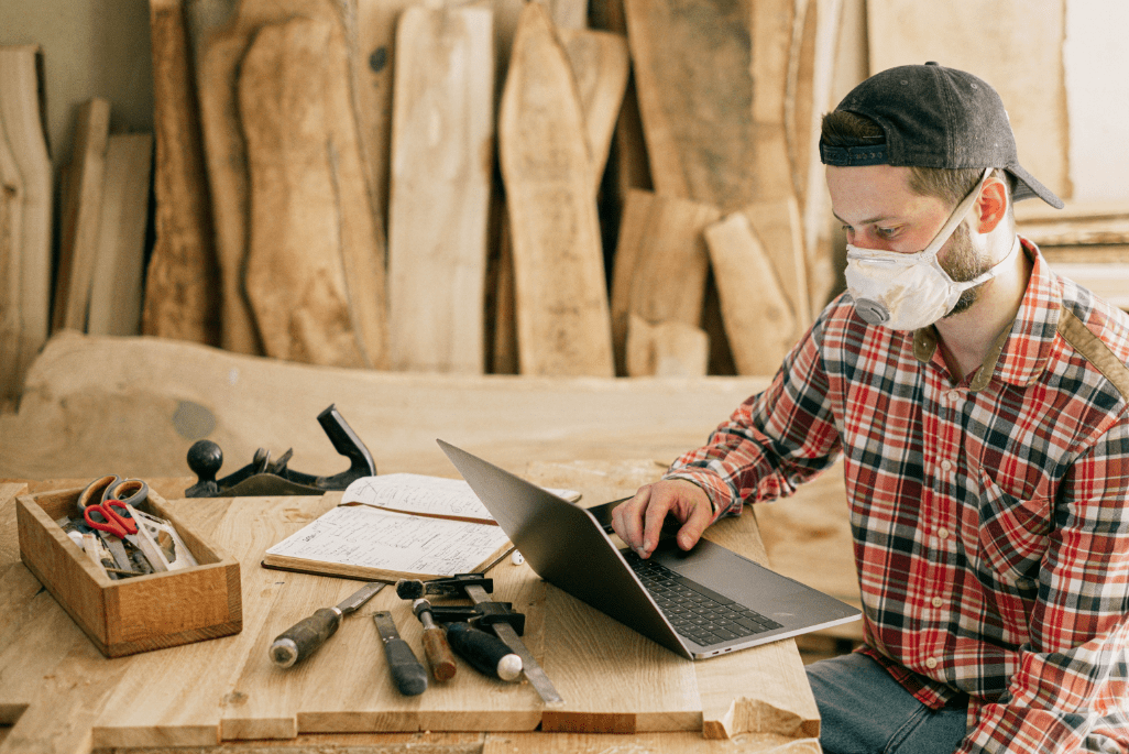 Man Using a Laptop at a Wood Workshop