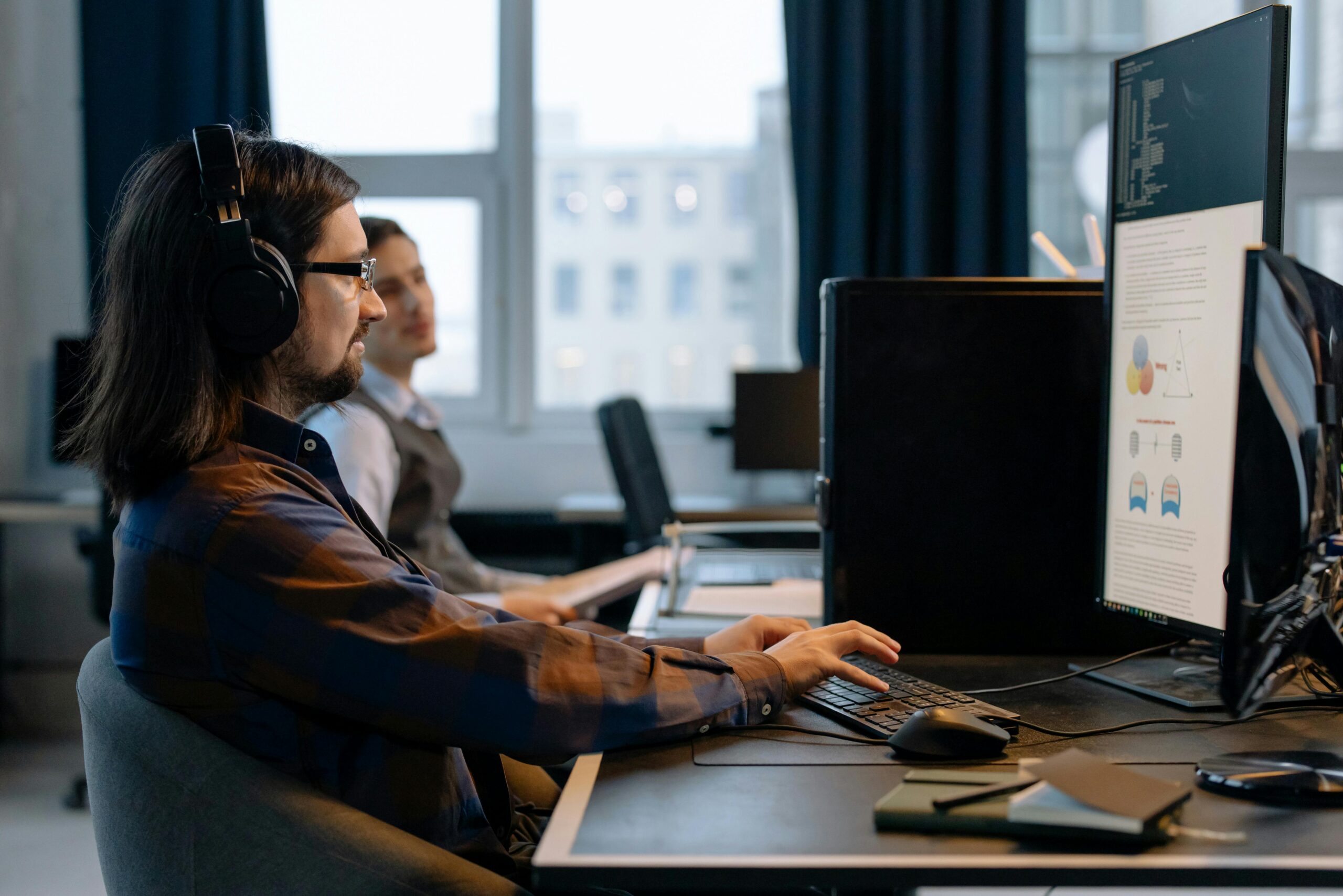 A software developer works on a custom software solution to streamline installation services, with data visualizations on his screen in a modern office setting.